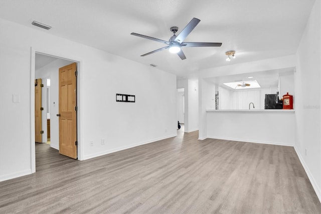 unfurnished living room with ceiling fan, light hardwood / wood-style floors, and sink