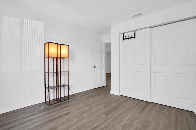 unfurnished bedroom with dark wood-type flooring and a closet