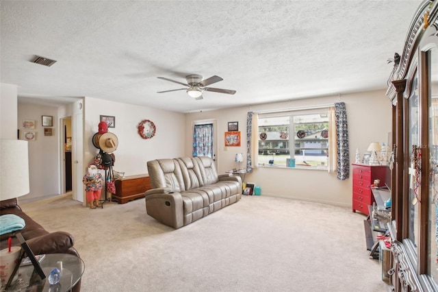 carpeted living room featuring ceiling fan and a textured ceiling