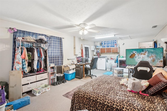 bedroom featuring washer and clothes dryer, ceiling fan, a textured ceiling, and light carpet