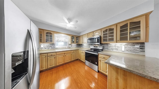 38919 3rd Ave, Zephyrhills, FL 33542 - kitchen with stainless steel appliances, light wood finished floors, a ceiling fan, glass insert cabinets, and tasteful backsplash
