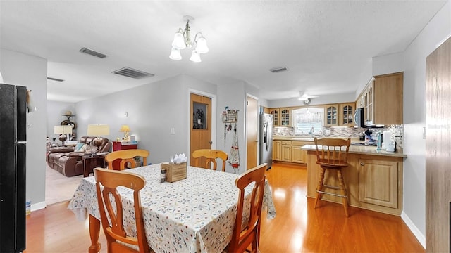 38919 3rd Ave, Zephyrhills, FL 33542 - dining space with light wood finished floors, a chandelier, and ceiling fan