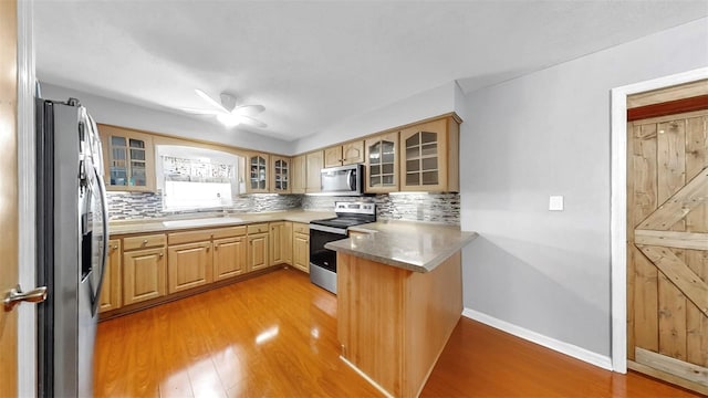 38919 3rd Ave, Zephyrhills, FL 33542 - kitchen with stainless steel appliances, a peninsula, light wood finished floors, and tasteful backsplash
