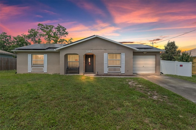 single story home featuring a yard, a garage, and solar panels