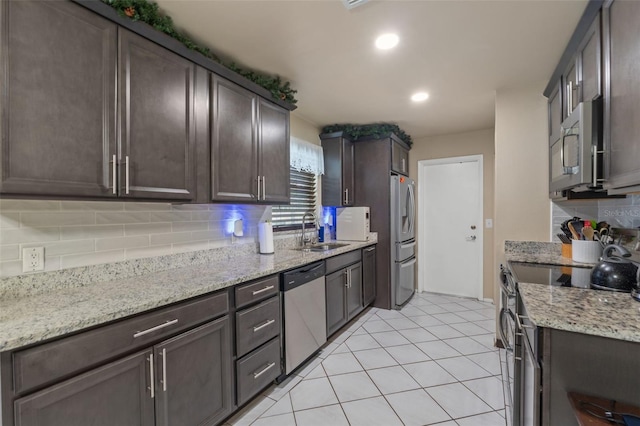 kitchen with light stone counters, sink, stainless steel appliances, and dark brown cabinets