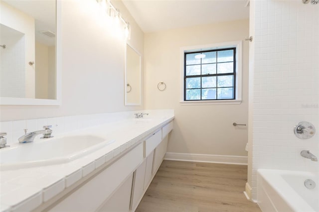 bathroom with hardwood / wood-style floors, vanity, and tiled shower / bath