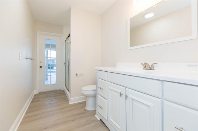 bathroom featuring hardwood / wood-style floors, vanity, toilet, and a shower with shower door