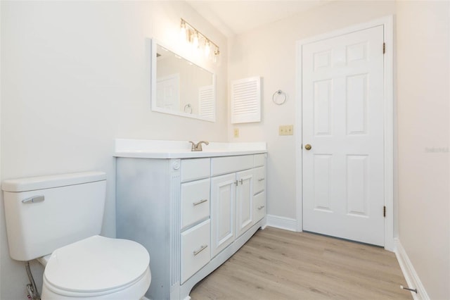 bathroom with wood-type flooring, vanity, and toilet