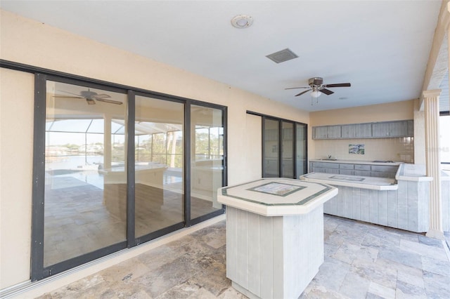 kitchen with gray cabinetry, ceiling fan, and a center island