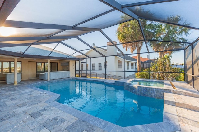 view of pool featuring glass enclosure, an in ground hot tub, and a patio