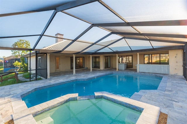 view of swimming pool featuring glass enclosure, an in ground hot tub, and a patio