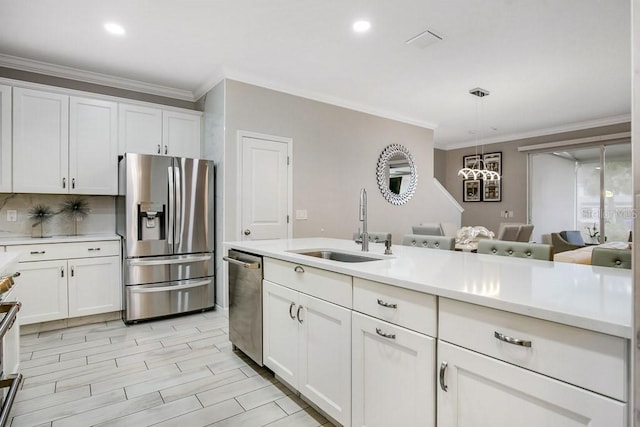 kitchen with sink, white cabinetry, stainless steel appliances, and hanging light fixtures