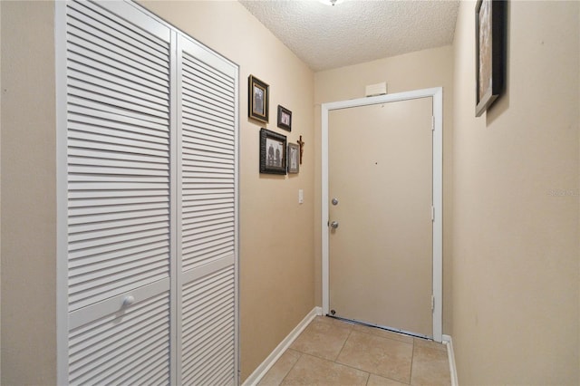 doorway to outside with light tile patterned floors and a textured ceiling