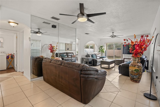 living room with light tile patterned floors, washer / dryer, and a textured ceiling