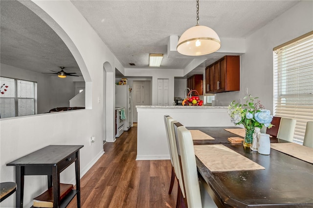 dining room featuring ceiling fan, dark wood-type flooring, and a textured ceiling