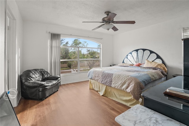 bedroom with ceiling fan, hardwood / wood-style flooring, and a textured ceiling