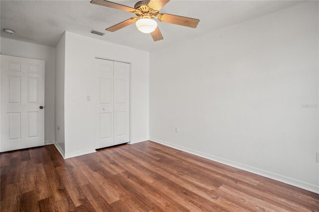 unfurnished bedroom featuring hardwood / wood-style flooring, ceiling fan, a closet, and a textured ceiling