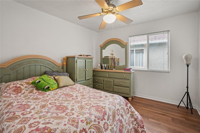 bedroom with ceiling fan, dark wood-type flooring, and a textured ceiling