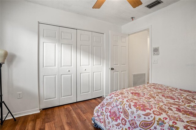 bedroom with ceiling fan, a textured ceiling, dark hardwood / wood-style flooring, and a closet