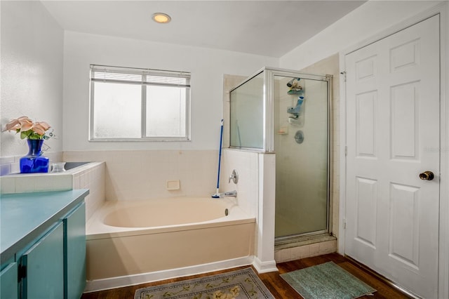 bathroom featuring wood-type flooring, vanity, and plus walk in shower