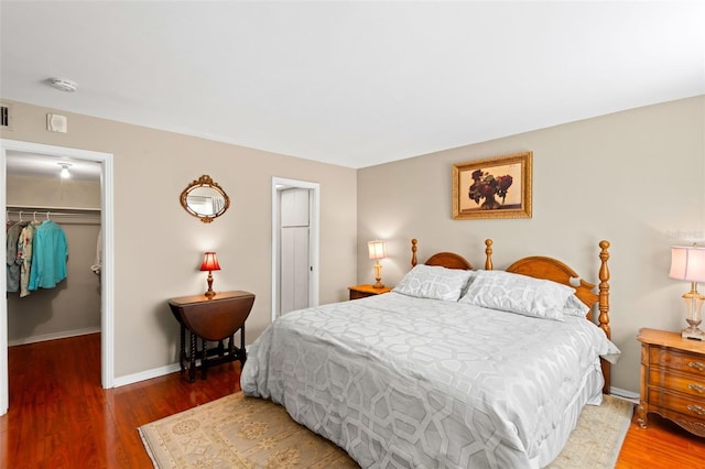 bedroom featuring a walk in closet, dark hardwood / wood-style floors, and a closet