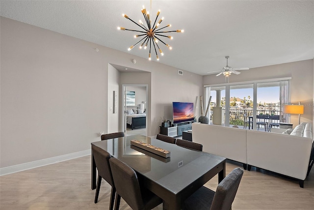 dining space with a textured ceiling, ceiling fan with notable chandelier, and light wood-type flooring