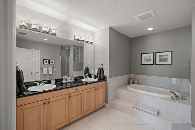 bathroom with tile patterned floors, separate shower and tub, vanity, and a textured ceiling