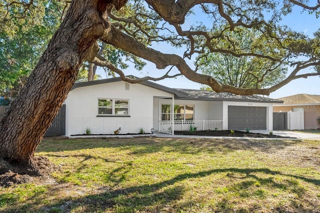 view of front of house featuring covered porch, a front yard, and a garage