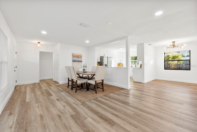 unfurnished dining area with a notable chandelier and light wood-type flooring