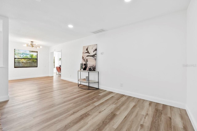 empty room featuring an inviting chandelier and light hardwood / wood-style floors