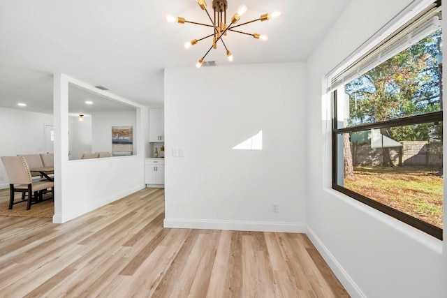 unfurnished room with light hardwood / wood-style flooring and a notable chandelier