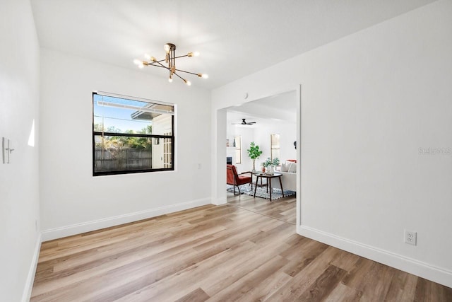 unfurnished room with ceiling fan with notable chandelier and light hardwood / wood-style floors