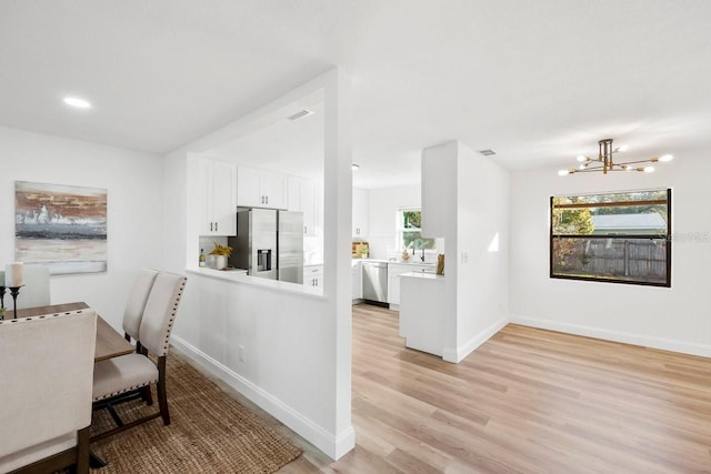 dining area with an inviting chandelier, light wood-type flooring, and a wealth of natural light