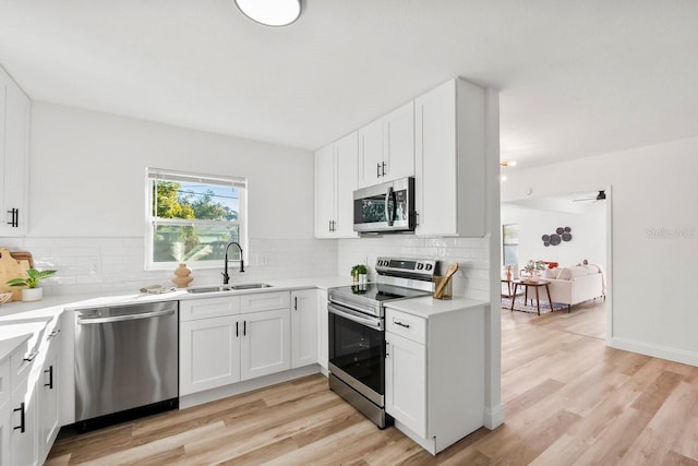 kitchen featuring appliances with stainless steel finishes, sink, decorative backsplash, and white cabinets