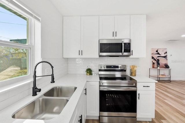 kitchen featuring tasteful backsplash, stainless steel appliances, sink, and white cabinets