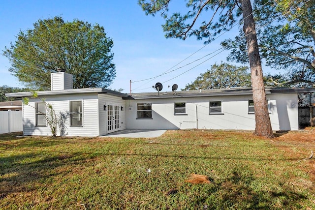 rear view of property with a lawn, french doors, and a patio area