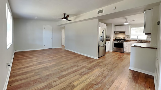 kitchen featuring white cabinets, sink, ceiling fan, light wood-type flooring, and appliances with stainless steel finishes