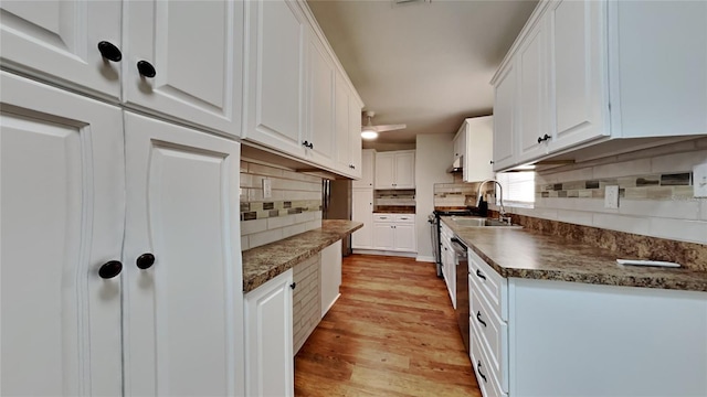 kitchen with white cabinets, stainless steel range oven, tasteful backsplash, and light hardwood / wood-style flooring