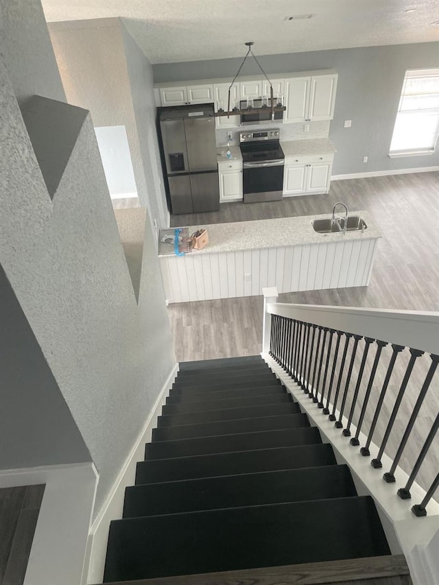 staircase with hardwood / wood-style flooring and sink