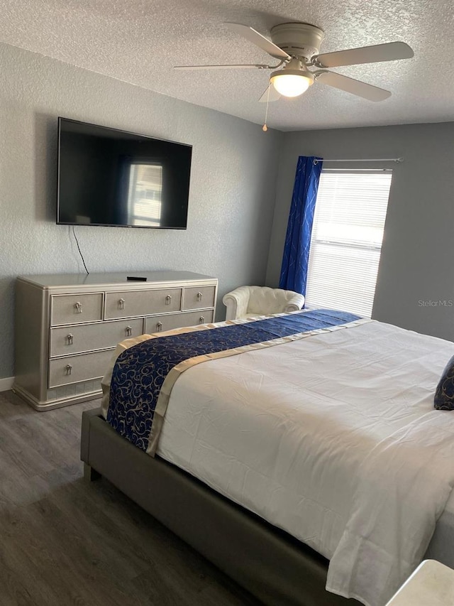 bedroom with ceiling fan, dark wood-type flooring, and a textured ceiling