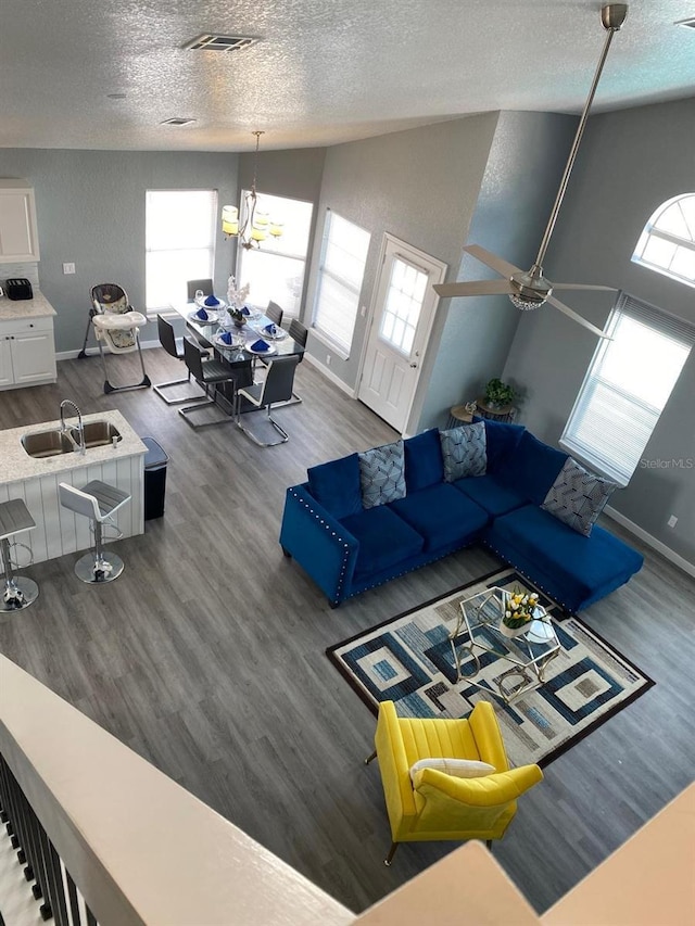 living room with a textured ceiling, hardwood / wood-style floors, vaulted ceiling, and sink