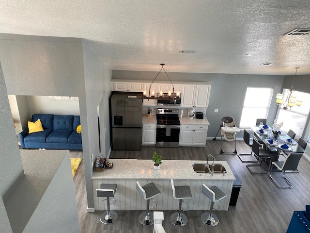 kitchen with white cabinets, hanging light fixtures, a breakfast bar area, kitchen peninsula, and stainless steel appliances