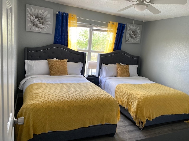 bedroom with hardwood / wood-style floors, ceiling fan, and a textured ceiling