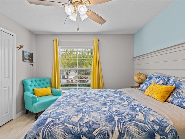 bedroom featuring ceiling fan, light hardwood / wood-style floors, and a textured ceiling