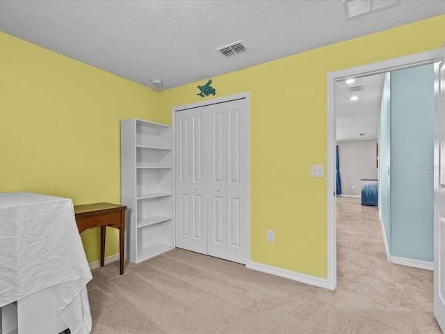 bedroom with a closet, light colored carpet, and a textured ceiling