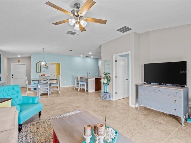 tiled living room with ceiling fan with notable chandelier and sink