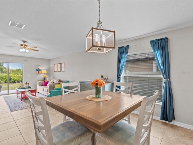 tiled dining space with ceiling fan with notable chandelier