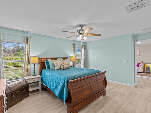 bedroom with multiple windows, ceiling fan, a textured ceiling, and light wood-type flooring