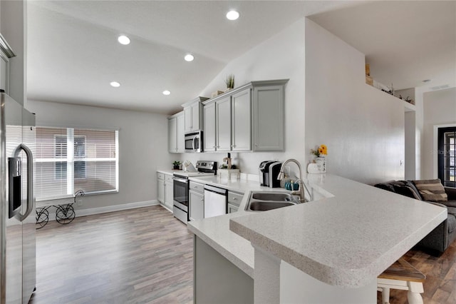 kitchen featuring sink, light hardwood / wood-style flooring, appliances with stainless steel finishes, a kitchen bar, and kitchen peninsula