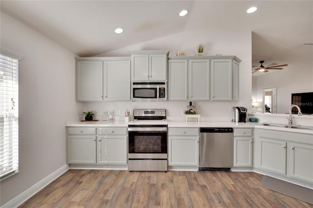 kitchen featuring sink, light hardwood / wood-style flooring, lofted ceiling, and appliances with stainless steel finishes